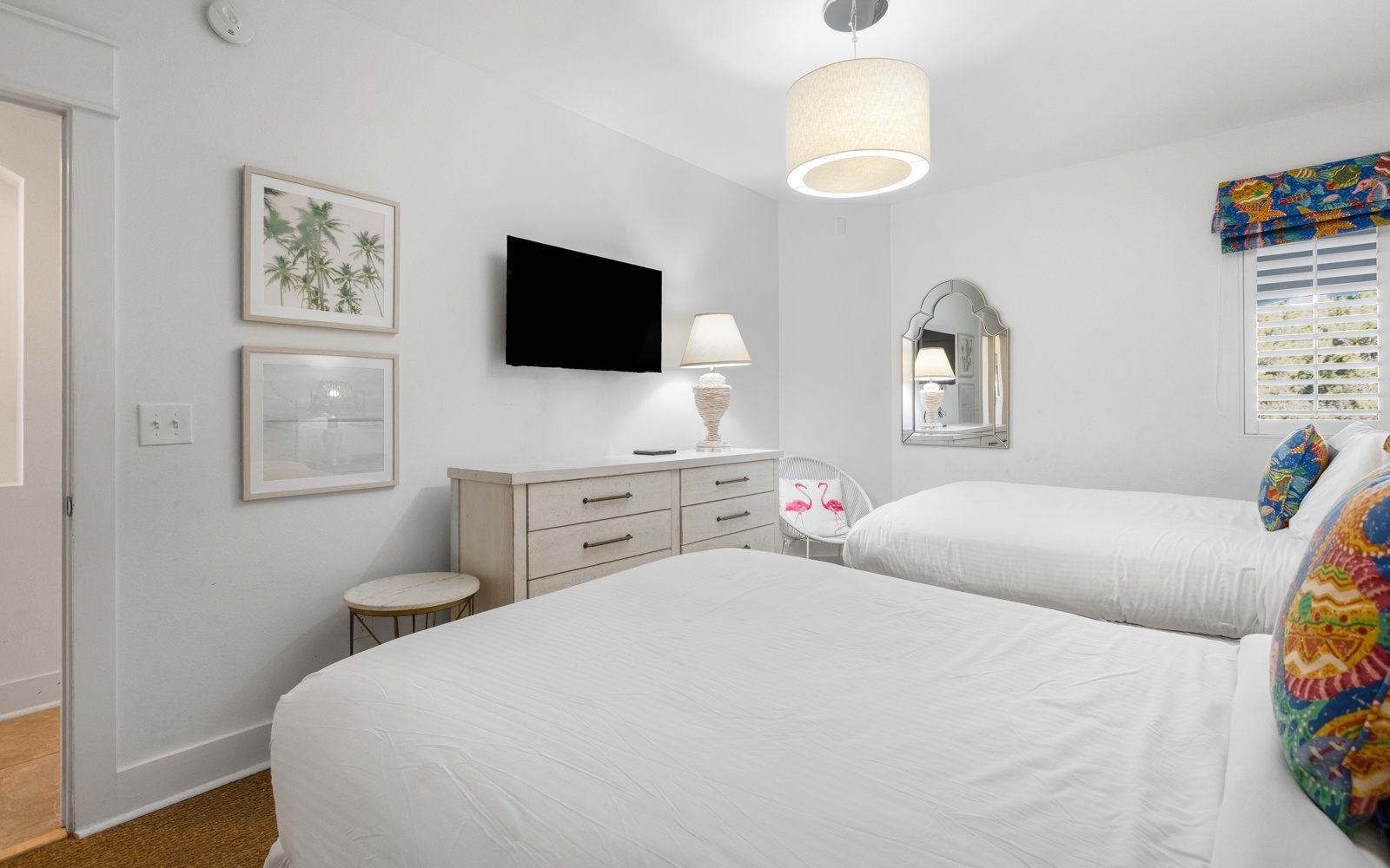 Sink into crisp white linens in your bright, tropical-themed bedroom with modern TV and thoughtful coastal touches for restful nights.