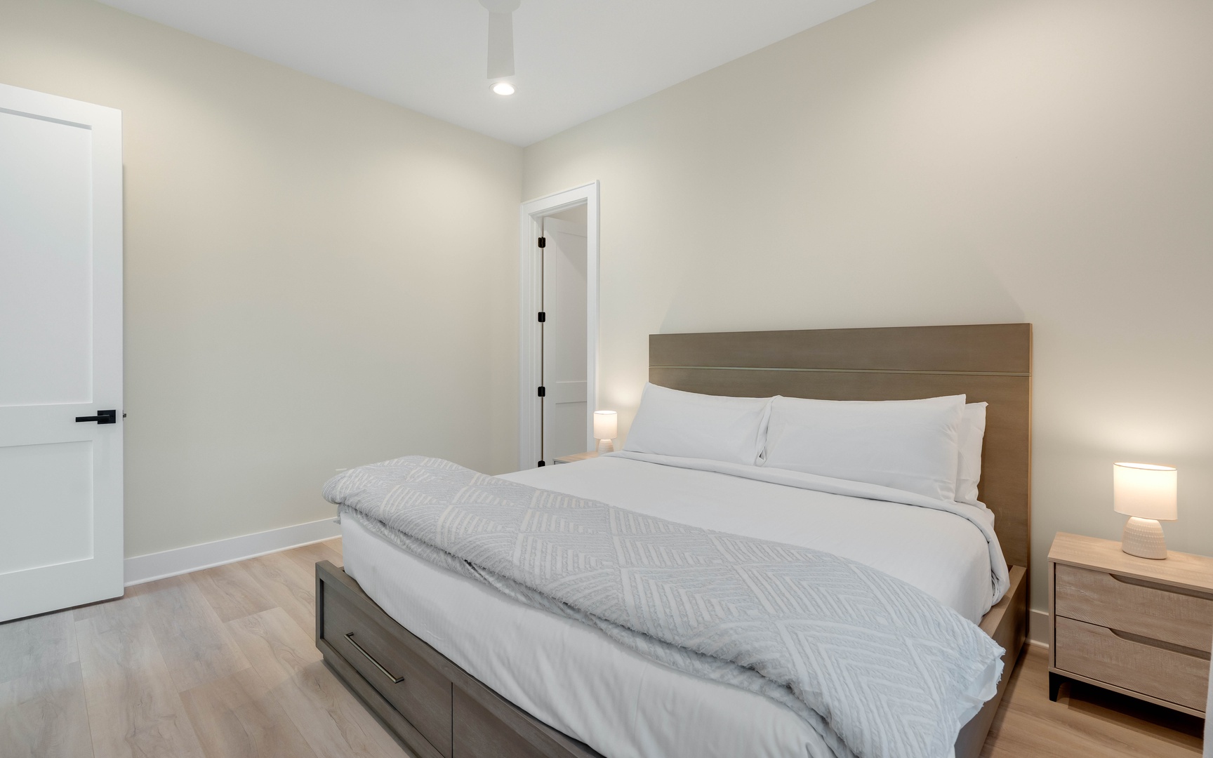 Sink into crisp white linens and wake up refreshed in your peaceful bedroom with modern wood furnishings and soft lighting.