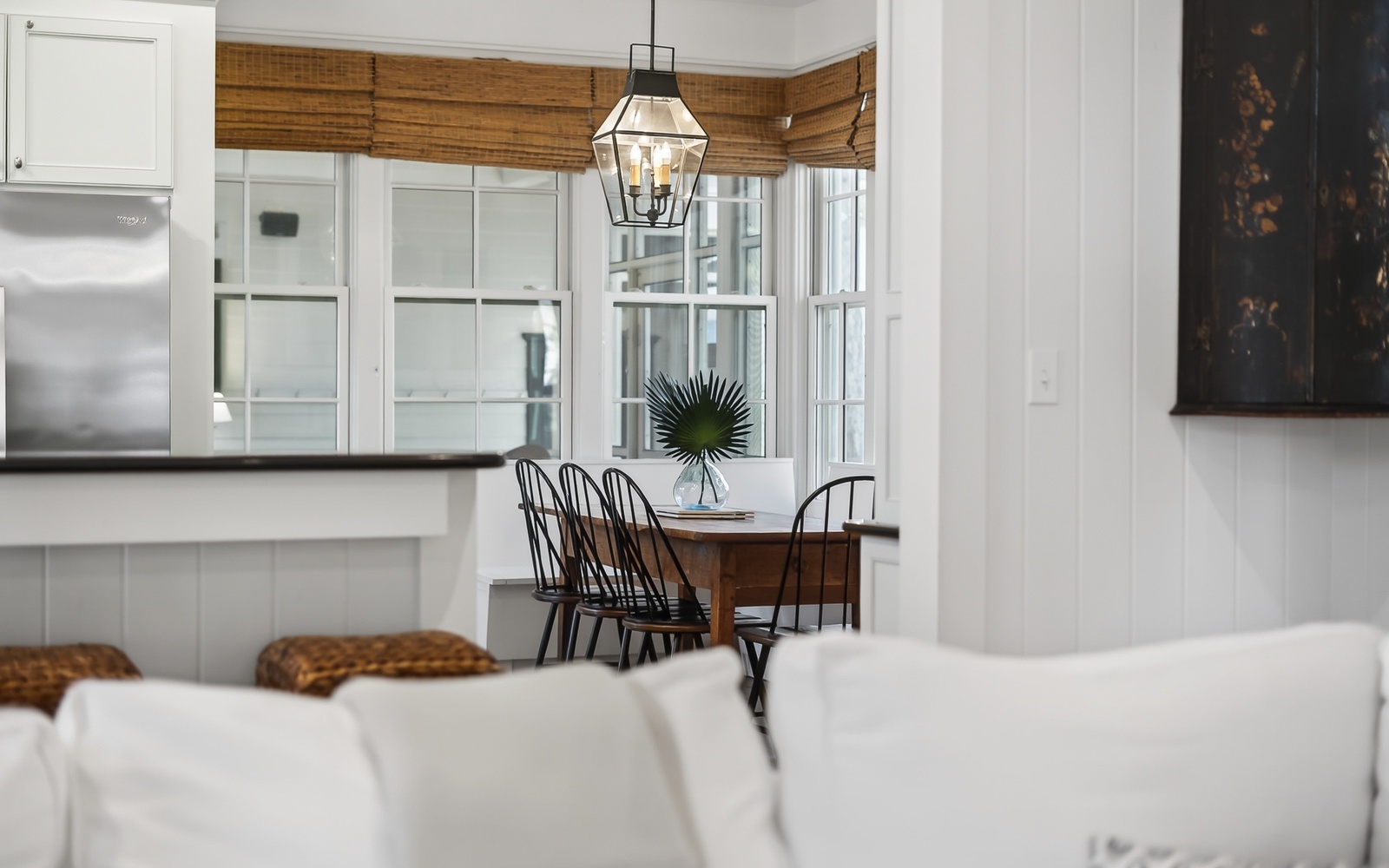 Gather around your bright dining nook where natural bamboo shades frame windows and elegant lighting creates the perfect ambiance for memorable meals.