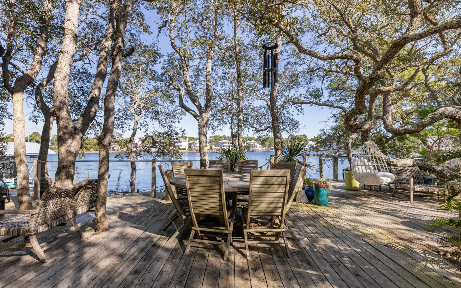 Dappled sunlight filters through ancient trees onto your private waterfront deck, where peaceful mornings unfold with coffee and stunning water views.