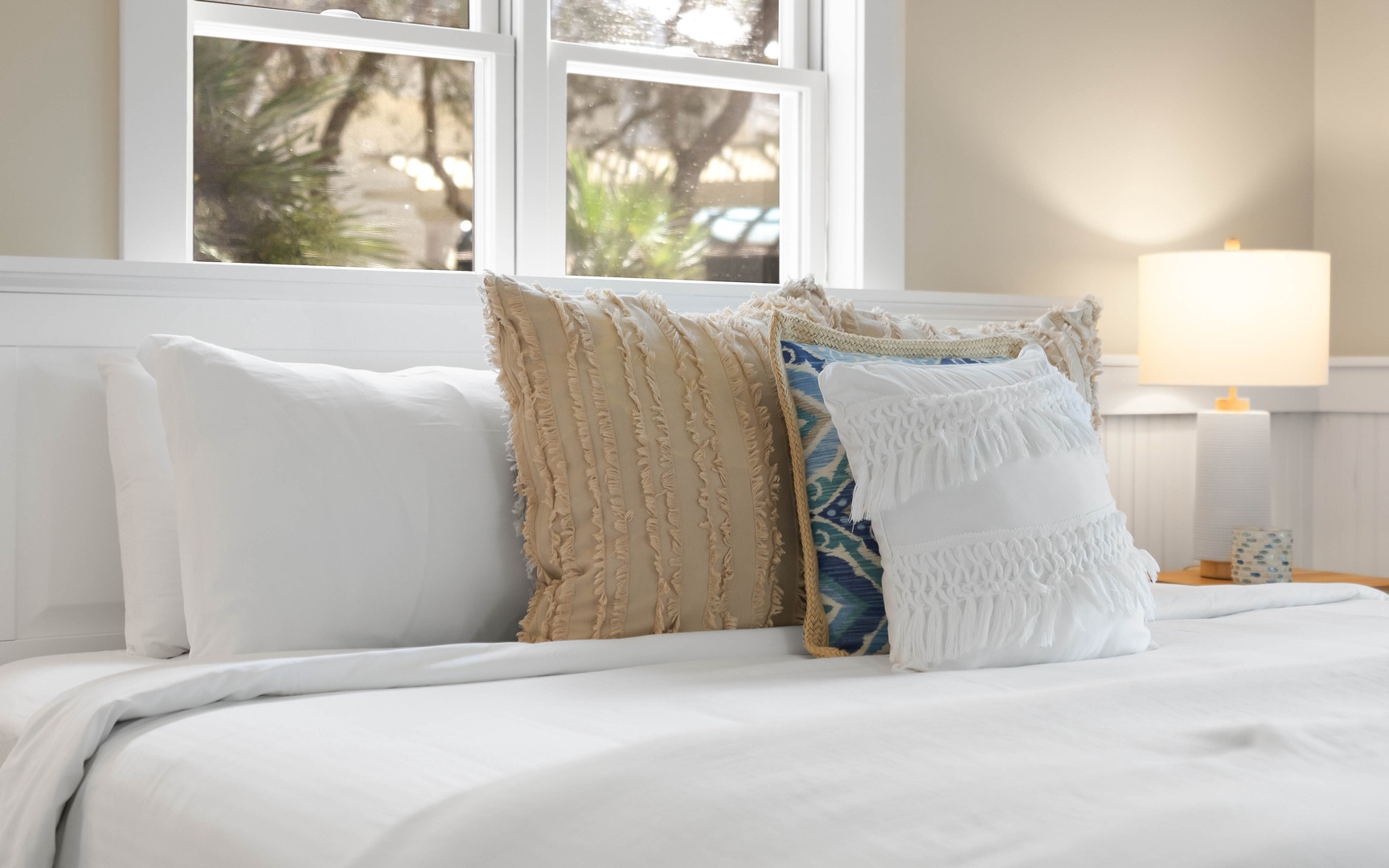 Sink into crisp white linens and plush pillows in your peaceful bedroom retreat, where natural light streams through charming windows.