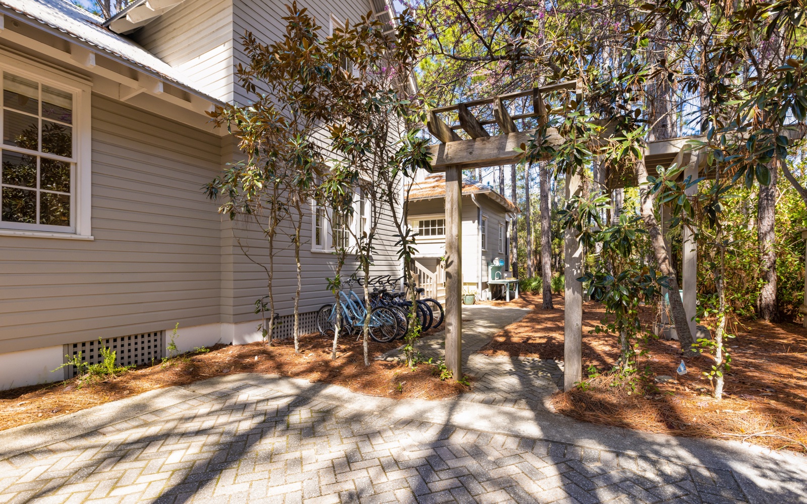 Charming property entrance with natural landscaping, bicycle parking, and peaceful residential setting.