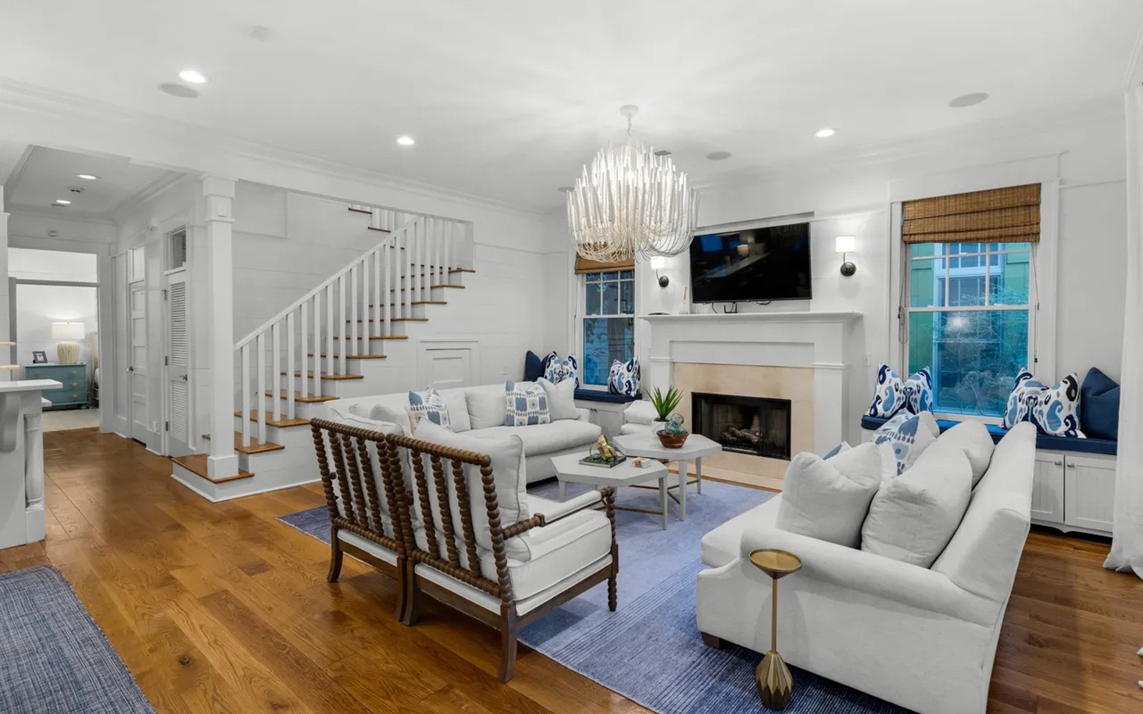 Sink into plush sofas in this elegant living room, where coastal blue accents and warm wood floors create your perfect retreat.