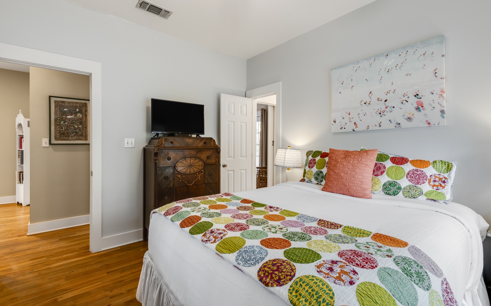 Unwind in your cheerful bedroom featuring vibrant bedding, vintage charm, and modern amenities like a flat-screen TV.