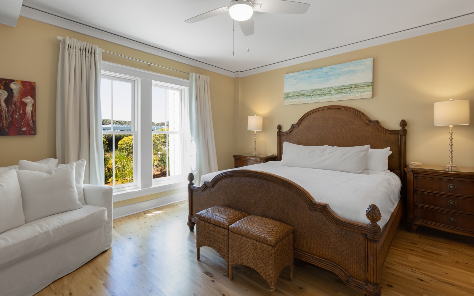 Drift off in your coastal bedroom with garden views through French doors and peaceful ocean artwork above crisp white linens.
