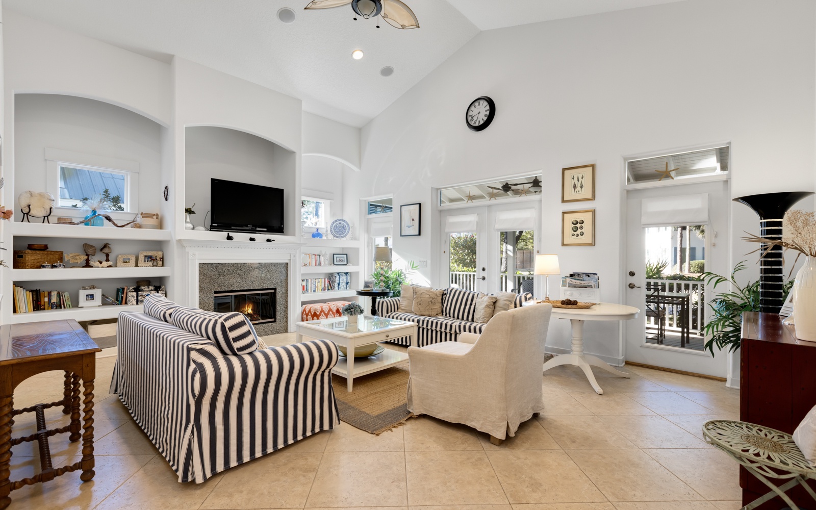 Your bright living space features cozy striped seating around a crackling fireplace, perfect for relaxing evenings with books from the built-in shelves.