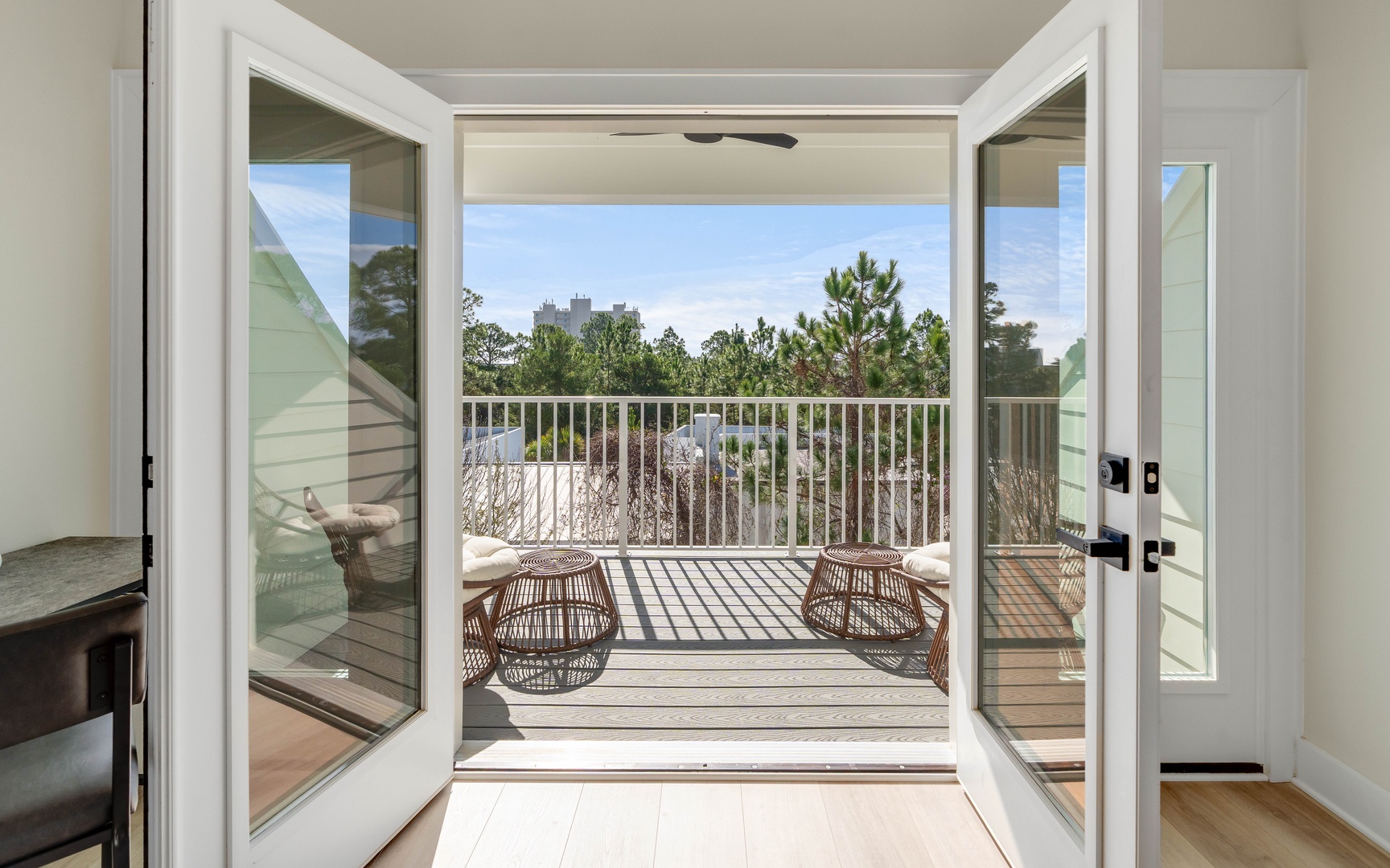 Step onto your private balcony where wicker seating awaits, framing peaceful treetop views and endless sky.