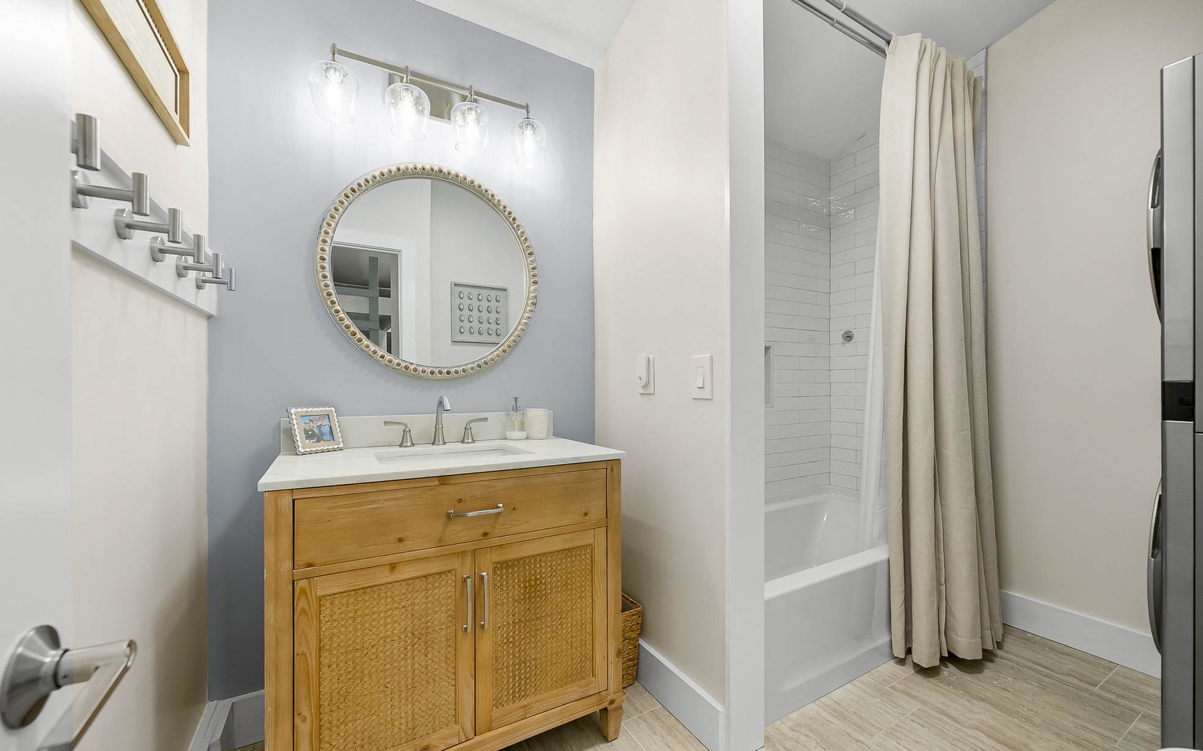 Step into your stylish bathroom featuring a warm wood vanity, elegant round mirror, and relaxing tub-shower combo perfect for unwinding.
