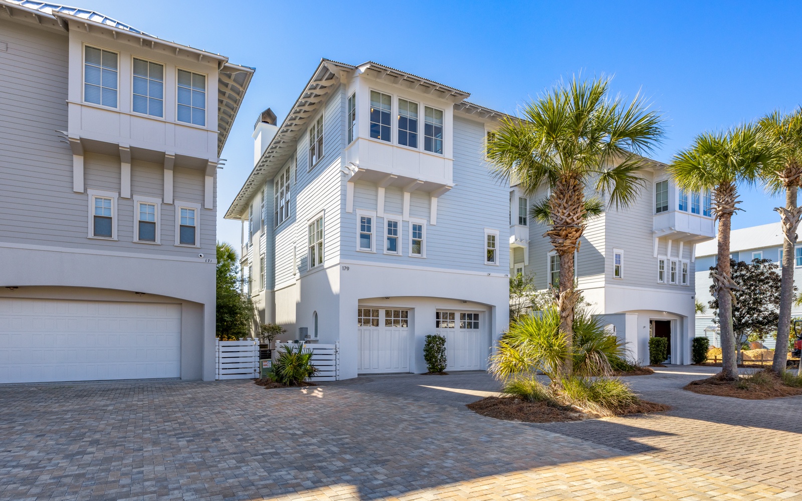 Modern coastal property featuring pristine white architecture, manicured landscaping, and convenient parking in a serene neighborhood setting.