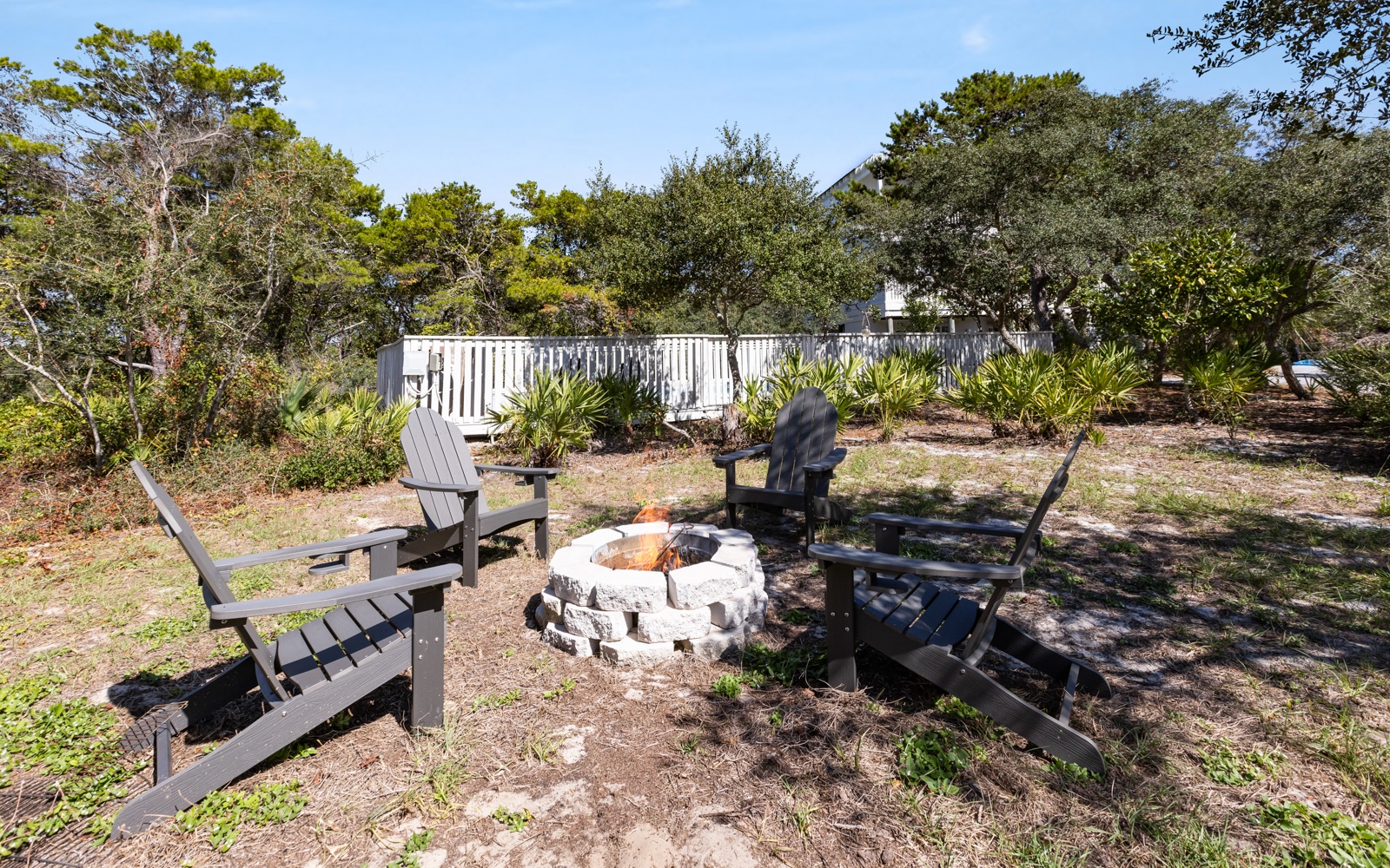 Gather around your private fire pit surrounded by Adirondack chairs, perfect for evening conversations under the stars in this peaceful backyard retreat.