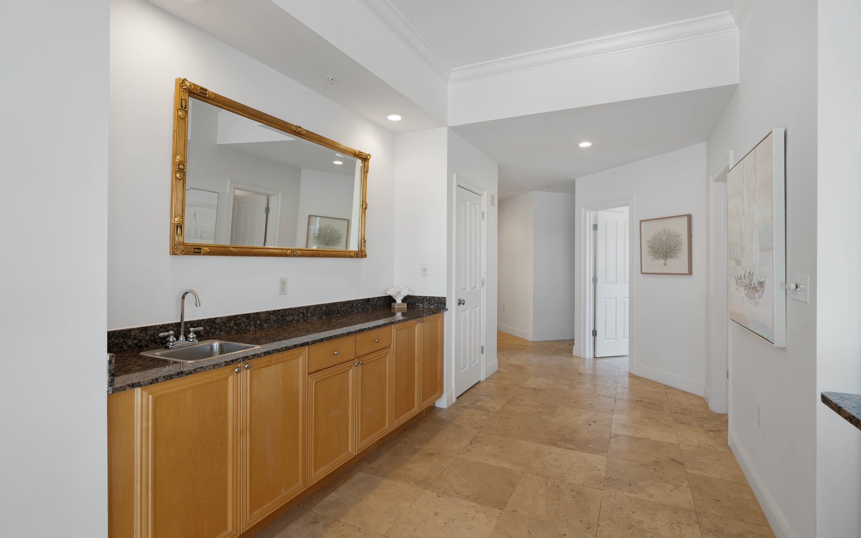Prepare meals in your bright, well-appointed kitchen with granite counters, rich wood cabinets, and elegant gold-framed mirror creating a refined cooking space.