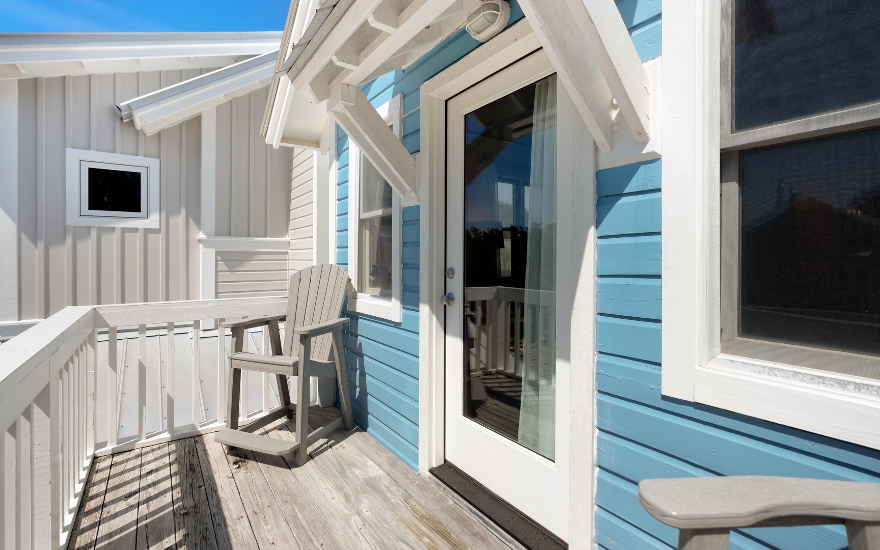 Step onto your private balcony where blue coastal siding meets white railings, creating the perfect spot to relax in comfort.
