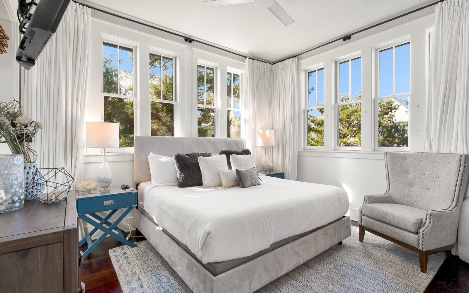 Wake up in this bright corner bedroom where natural light streams through floor-to-ceiling windows and crisp white linens invite your peaceful rest.