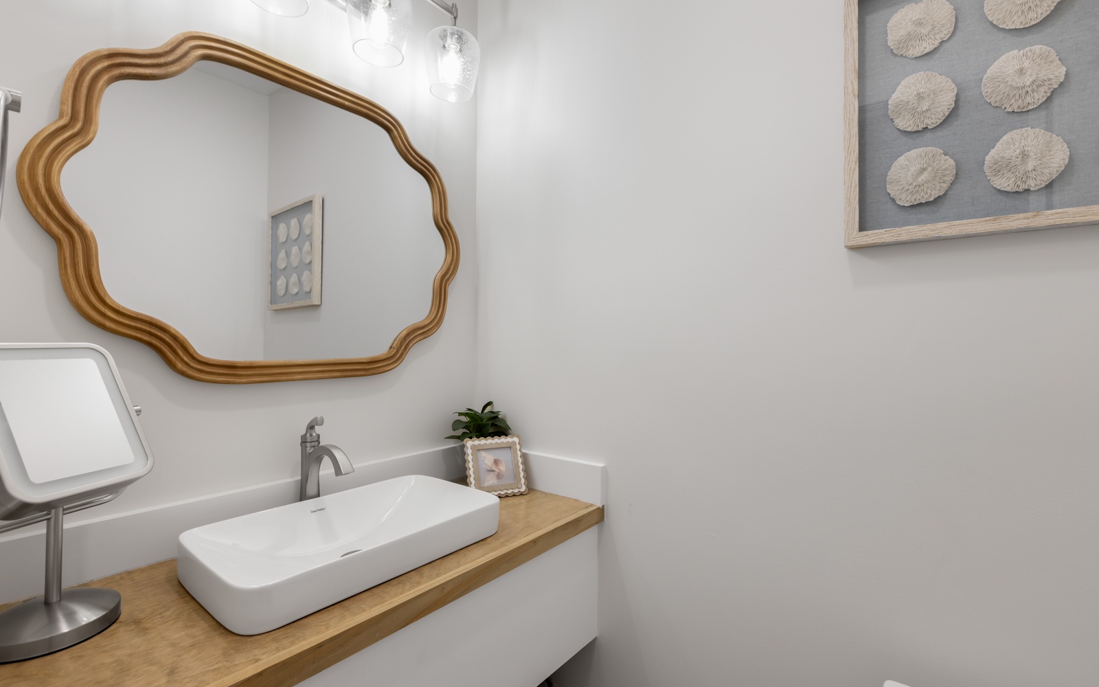 Fresh up in your stylish powder room with elegant gold mirror and coastal touches.