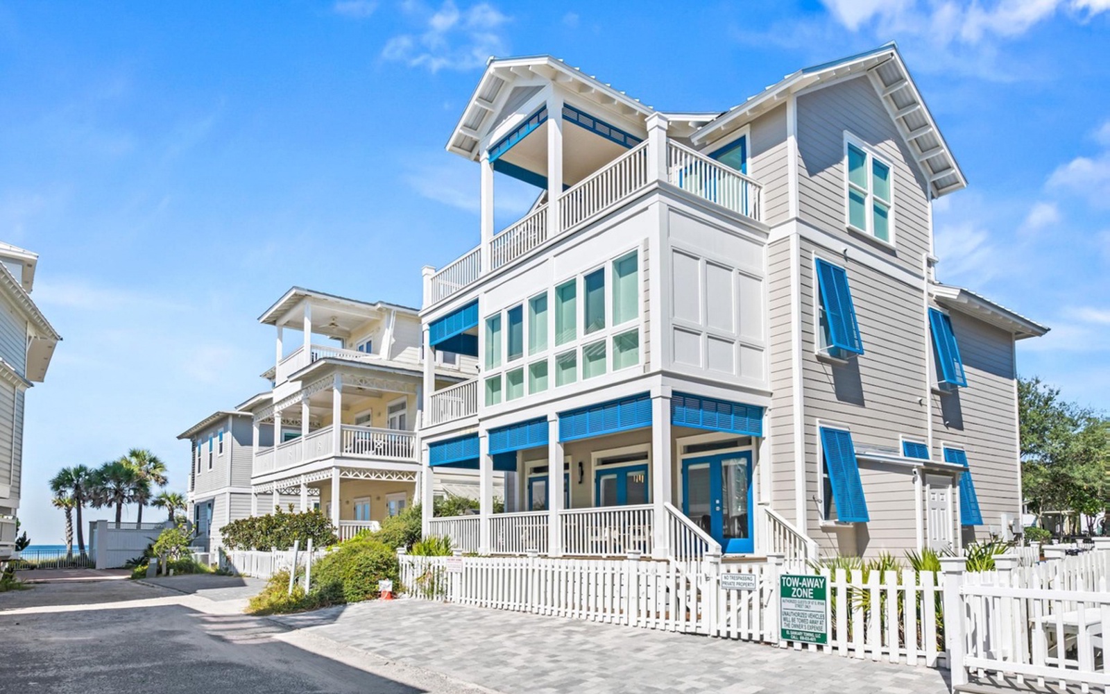 Beautiful coastal property with bright blue accents, multiple balconies, and charming white picket fence in a peaceful neighborhood setting.