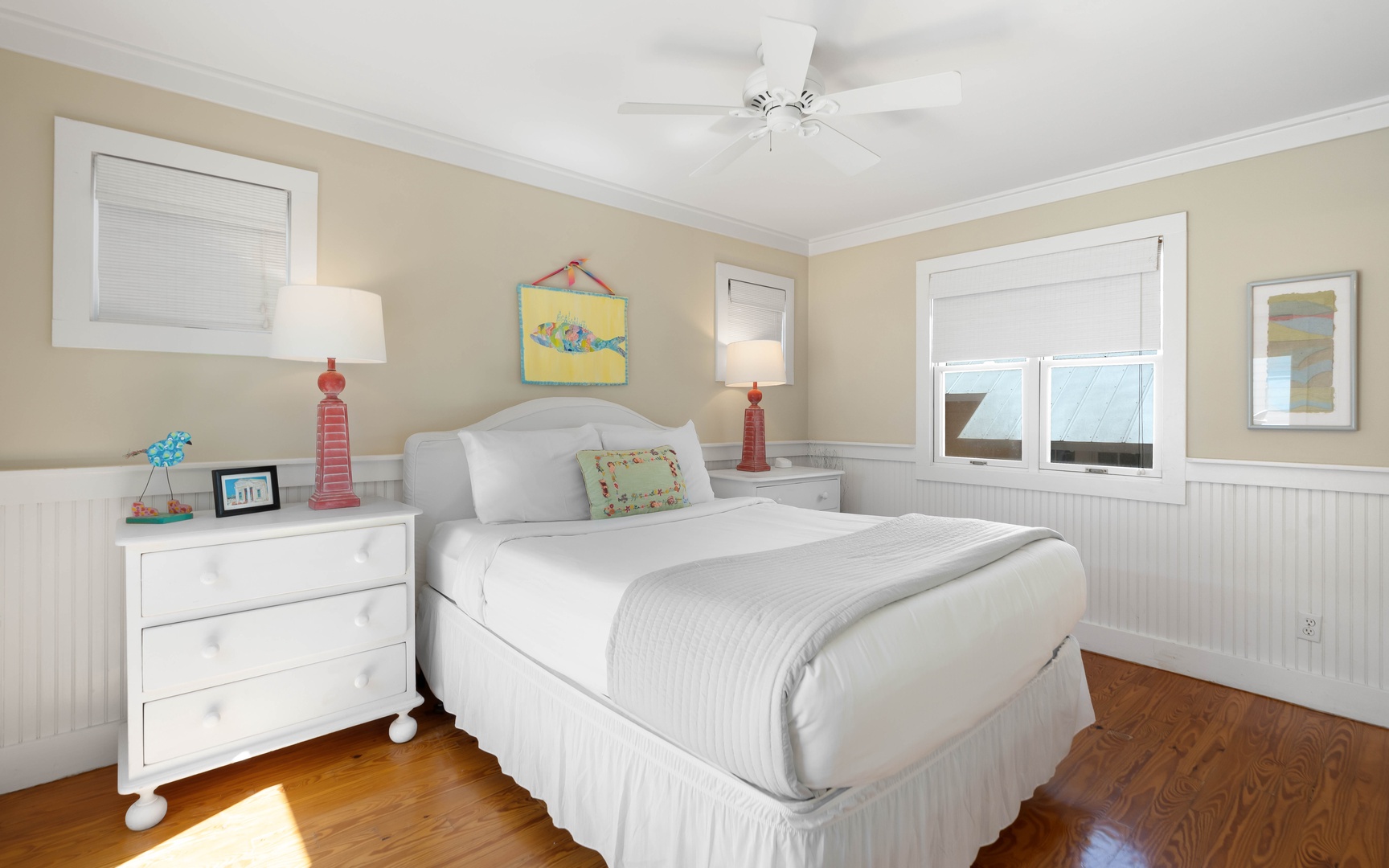 Rest peacefully in your bright coastal bedroom with crisp linens, cheerful artwork, and gentle ceiling fan keeping you cool.