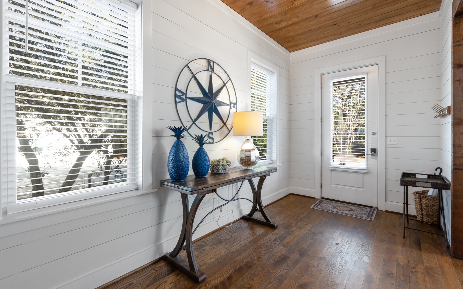 Step into your charming coastal-inspired entryway, where natural light streams through custom blinds and warm wood floors welcome you home.