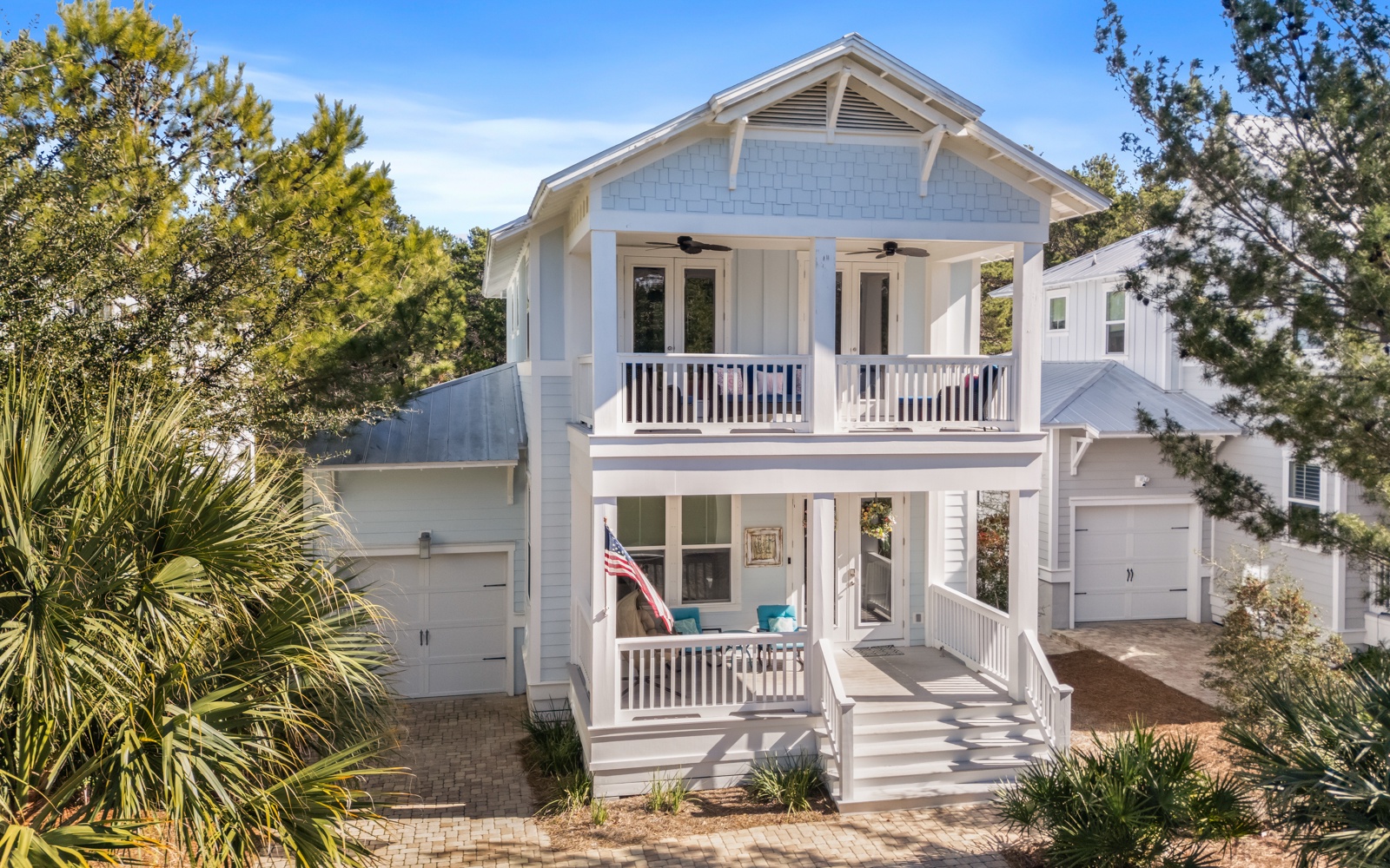 Charming coastal cottage with double-story porches and tropical landscaping creates the perfect beach getaway retreat.