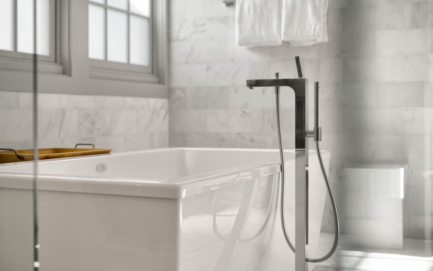 Sink into the sleek marble bathtub where natural light streams through elegant windows, creating your perfect retreat.