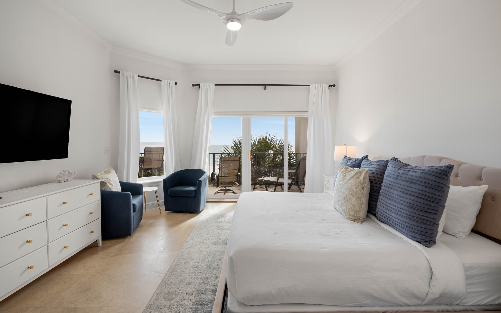 Wake to coastal views from your bright bedroom, complete with balcony access and thoughtful touches like cozy seating.