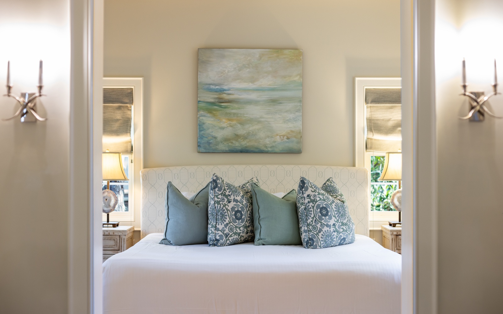 Slip into your serene bedroom sanctuary where ocean-inspired artwork and soft blue pillows create the perfect coastal retreat for restful nights.