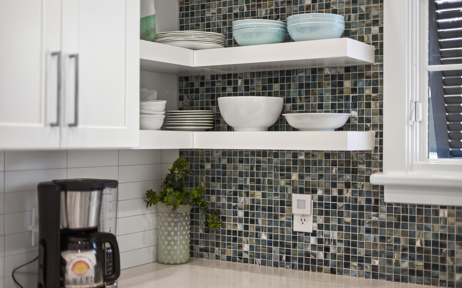 Your fully equipped kitchen features elegant open shelving with quality dishes and a stylish mosaic backsplash for your culinary adventures.