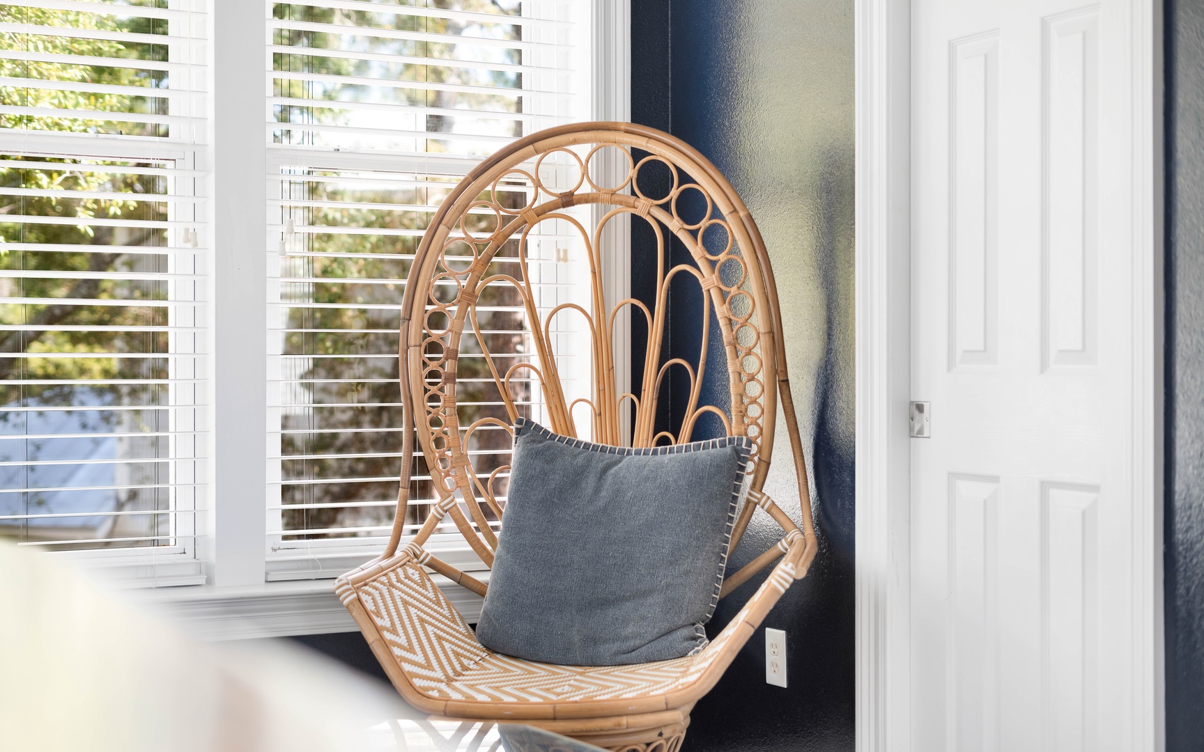 Sink into this cozy peacock chair, where natural light and soft cushions create your perfect reading nook.