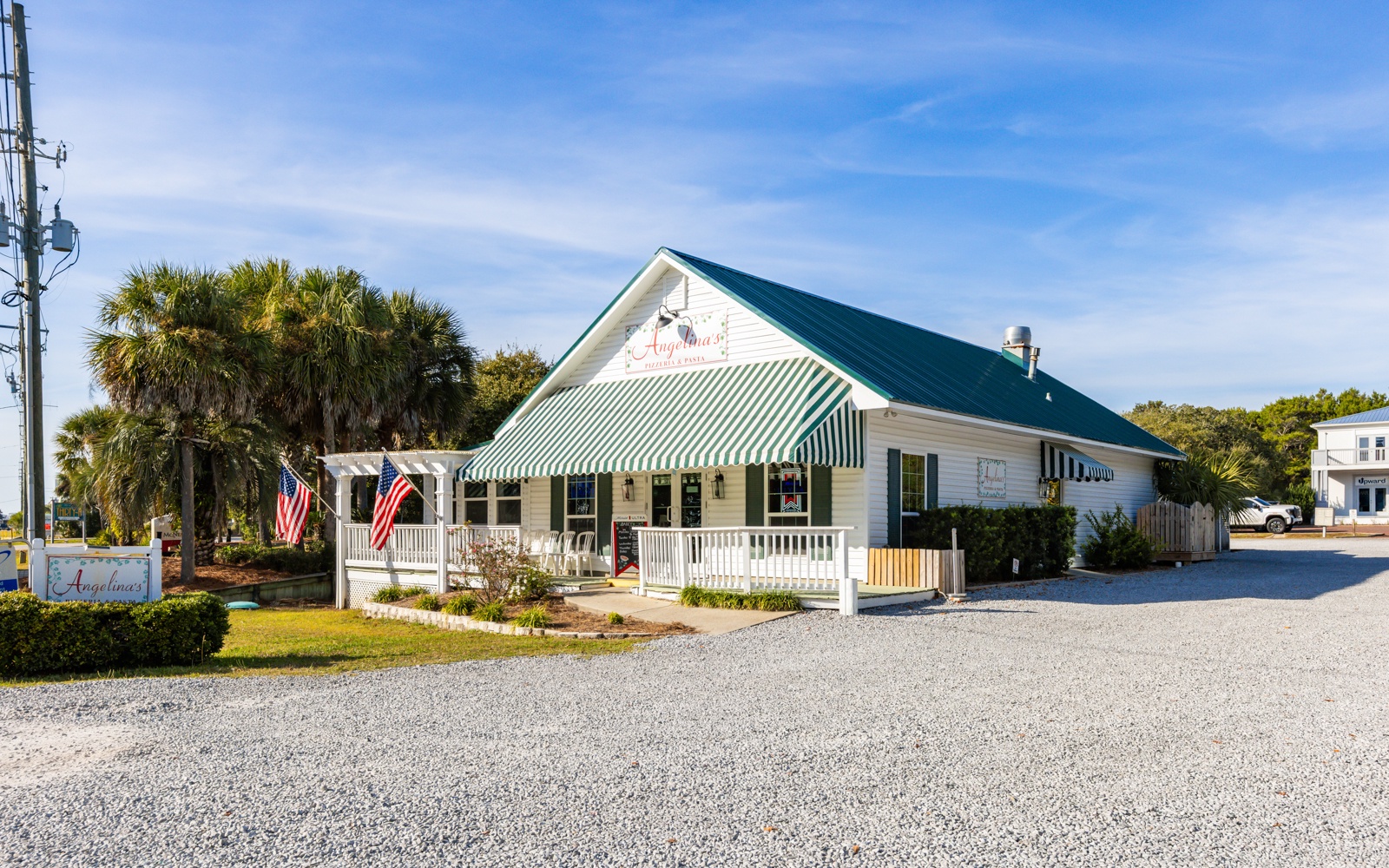 A charming coastal restaurant with striped awnings and white picket fencing creates a welcoming dining destination in this waterfront community.