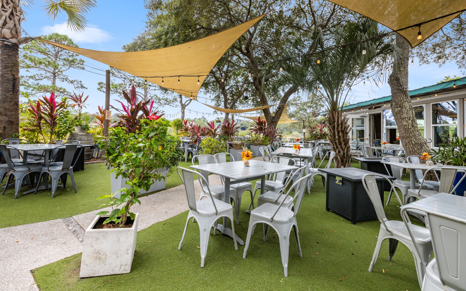 Dine al fresco under tropical shade sails where lush gardens and palm trees create your perfect outdoor retreat.