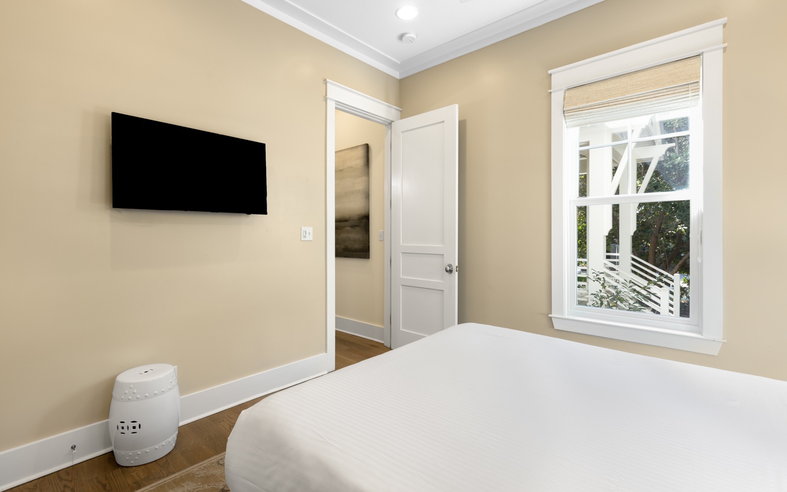 Relax in your serene bedroom with plush bedding, elegant decor, and a wall-mounted TV for cozy evenings.