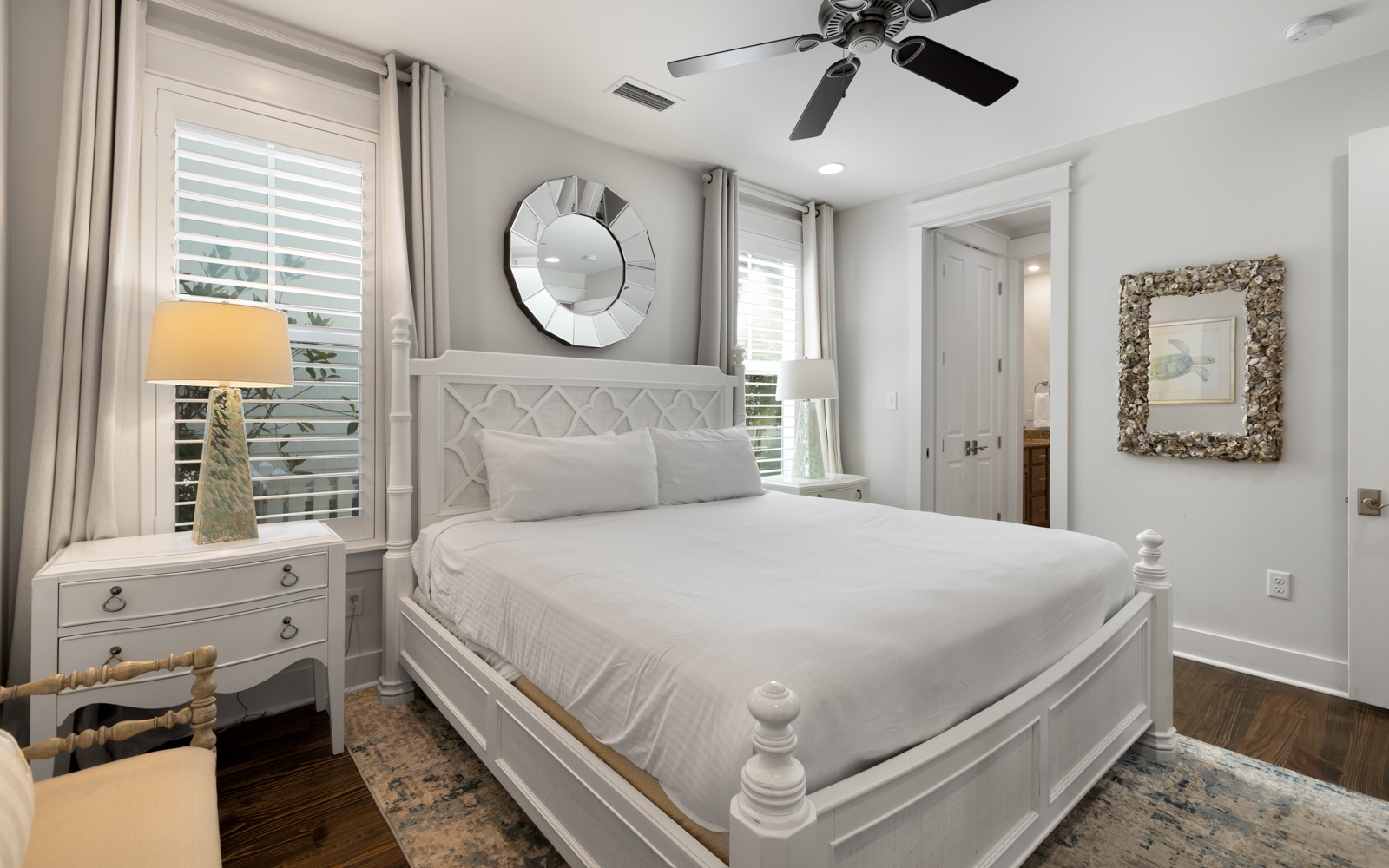 Drift off in your serene white bedroom with plush linens, coastal charm, and gentle ceiling fan keeping you cool.