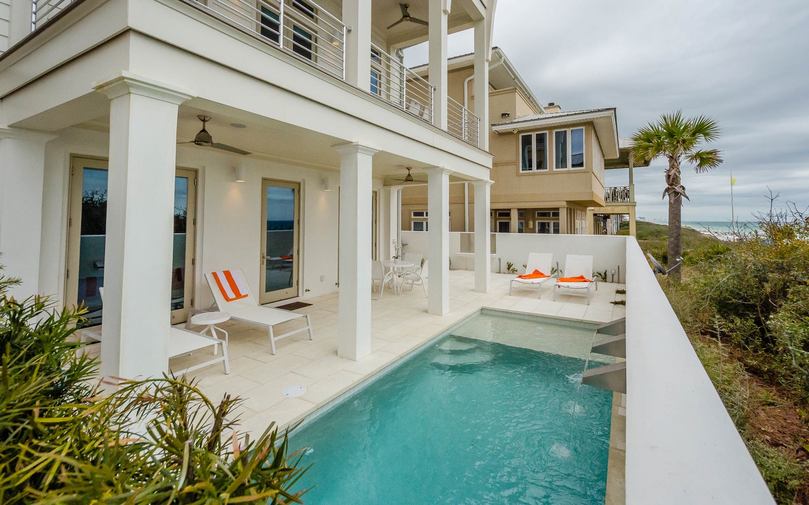 Modern beachside villa with pristine pool and tropical gardens in a serene coastal setting.