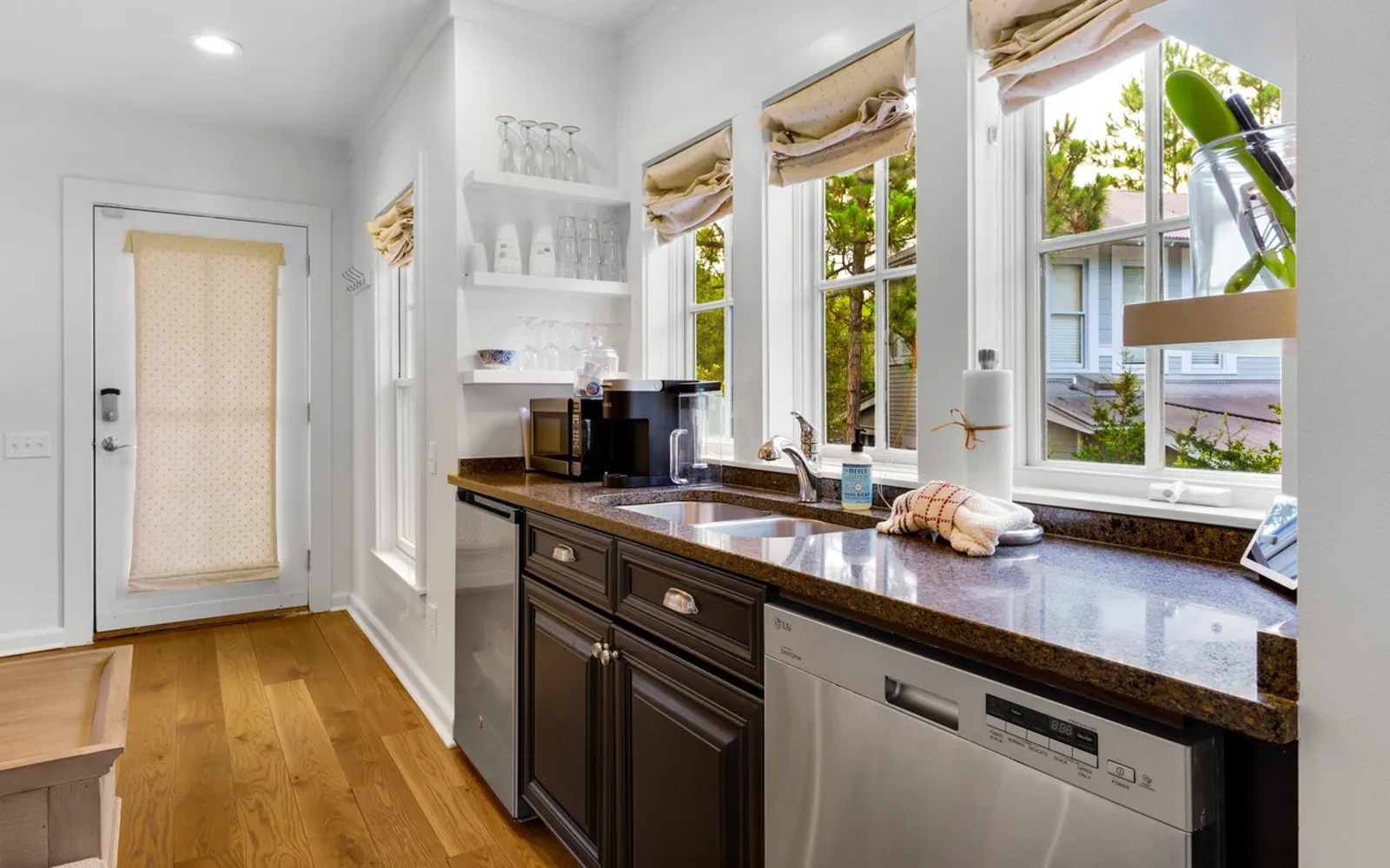 Your bright, fully-equipped kitchen awaits with granite counters, stainless appliances, and windows overlooking lush greenery.