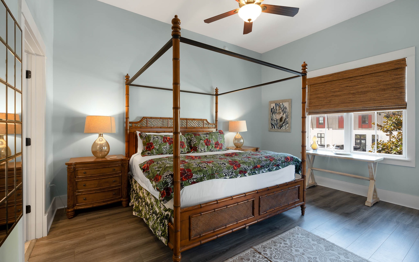 Relax in your elegant four-poster bed beneath a gentle ceiling fan, with soft morning light filtering through bamboo blinds.