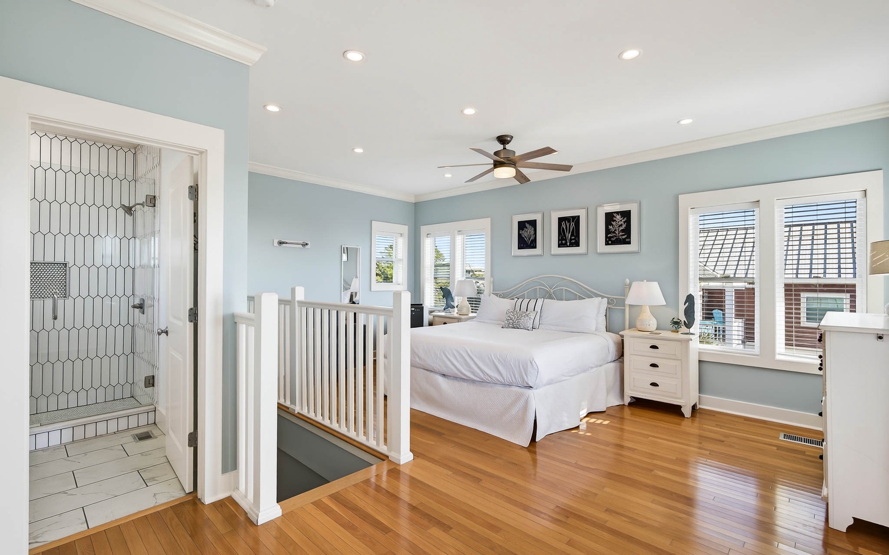 Your peaceful master bedroom features soothing blue walls, gleaming hardwood floors, and a spa-like ensuite with stylish hexagonal tile shower.