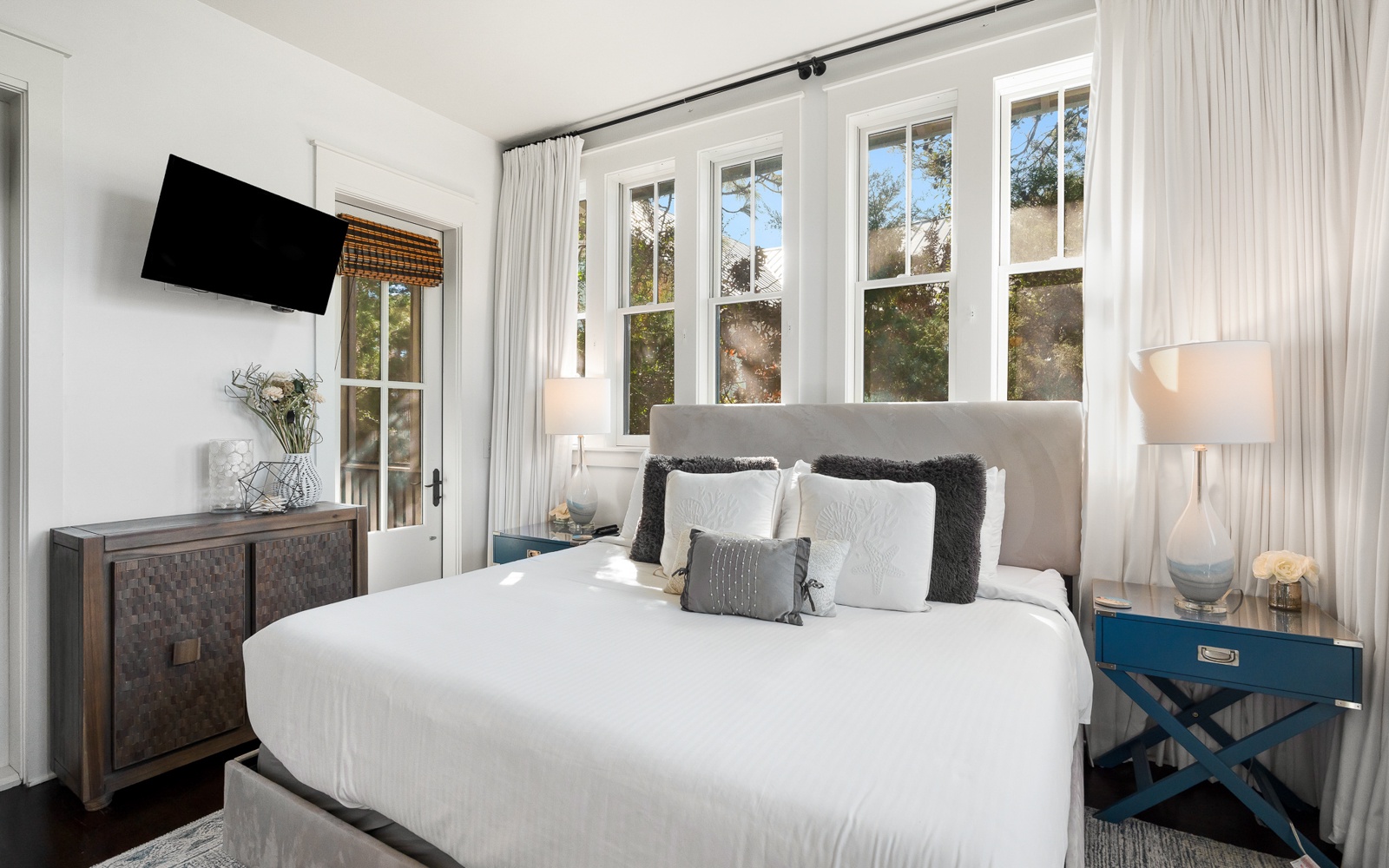 Unwind in your elegant bedroom with crisp white linens, natural light streaming through French doors, and modern amenities for ultimate comfort.