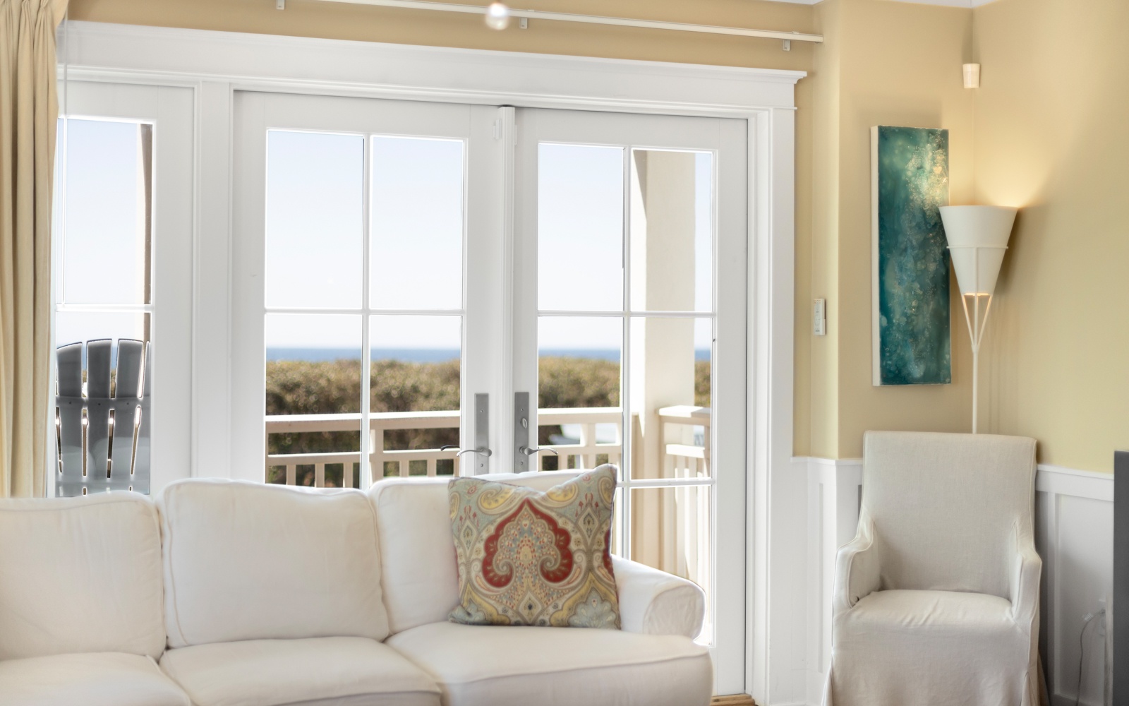 Unwind in your bright, airy living space where French doors open to reveal stunning ocean views and comfortable seating awaits.