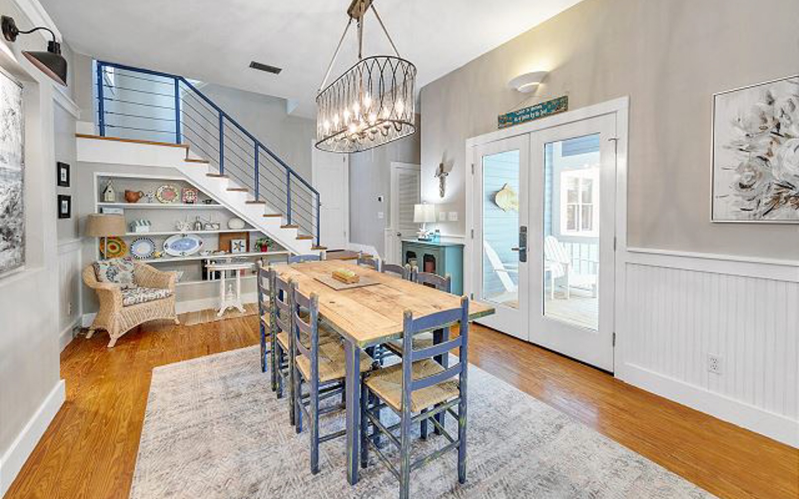Gather around your stylish dining table beneath the statement chandelier, with warm hardwood floors and charming coastal touches creating the perfect space for memorable meals.