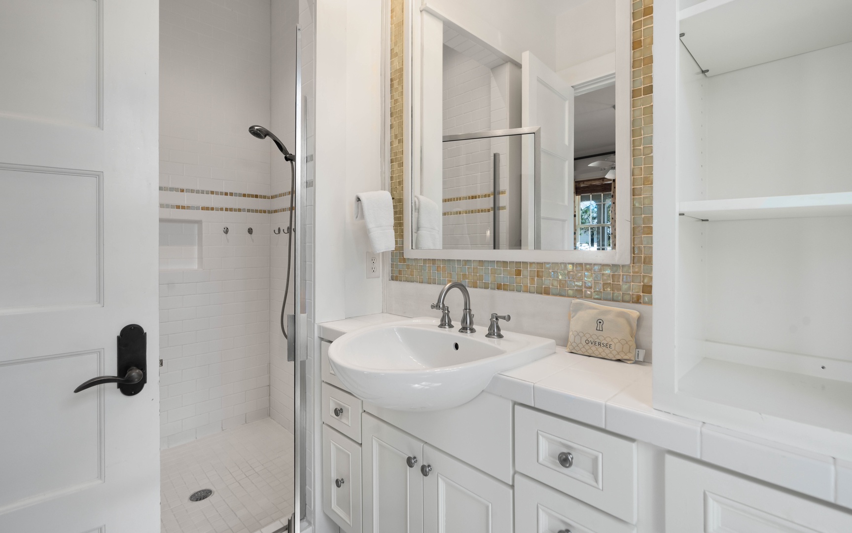 Step into your elegant ensuite bathroom featuring a spacious glass shower, stylish mosaic tile accents, and a pristine vanity with ample storage.