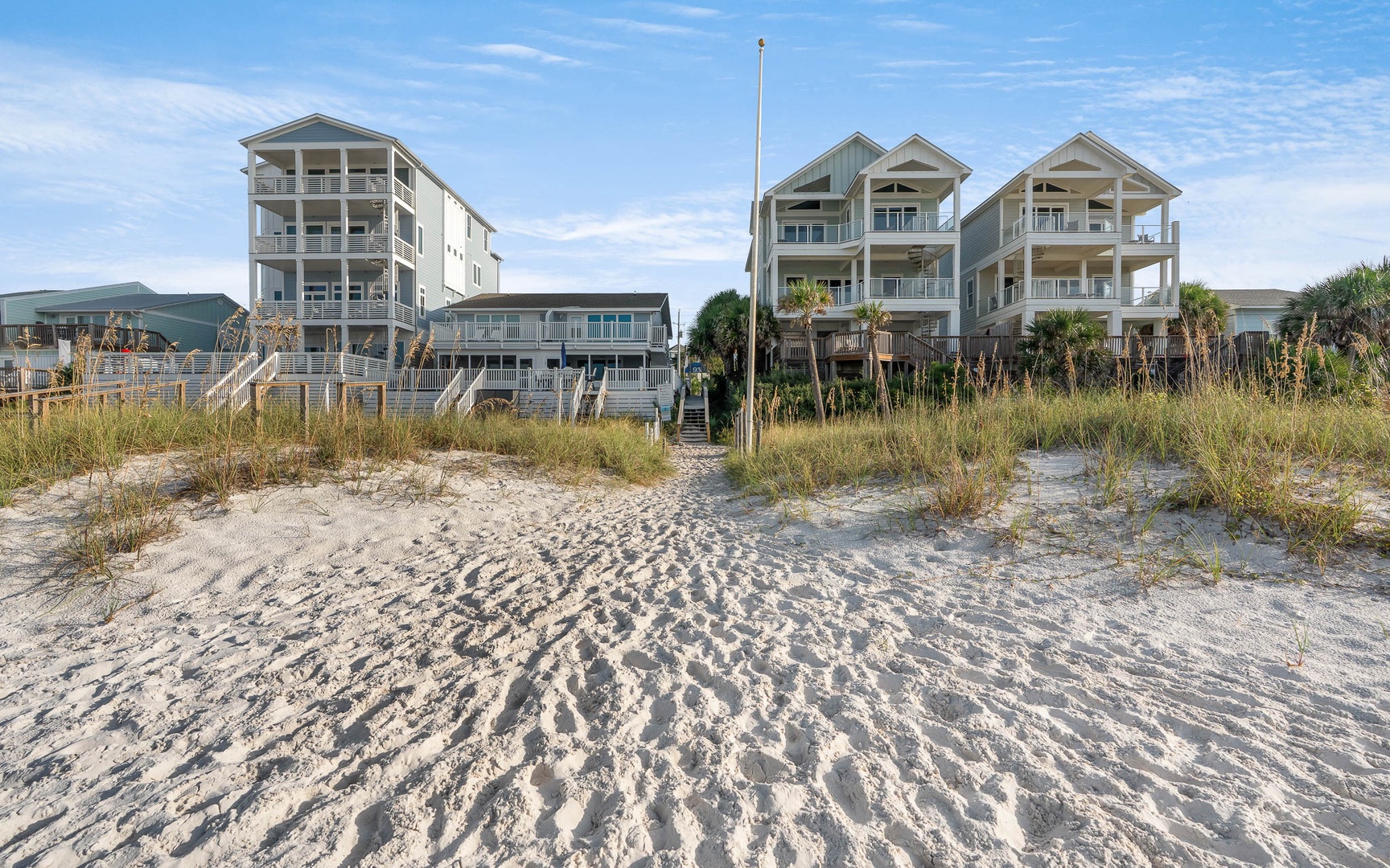Beachfront vacation homes line pristine white sand, offering direct beach access with coastal views and sea breezes.