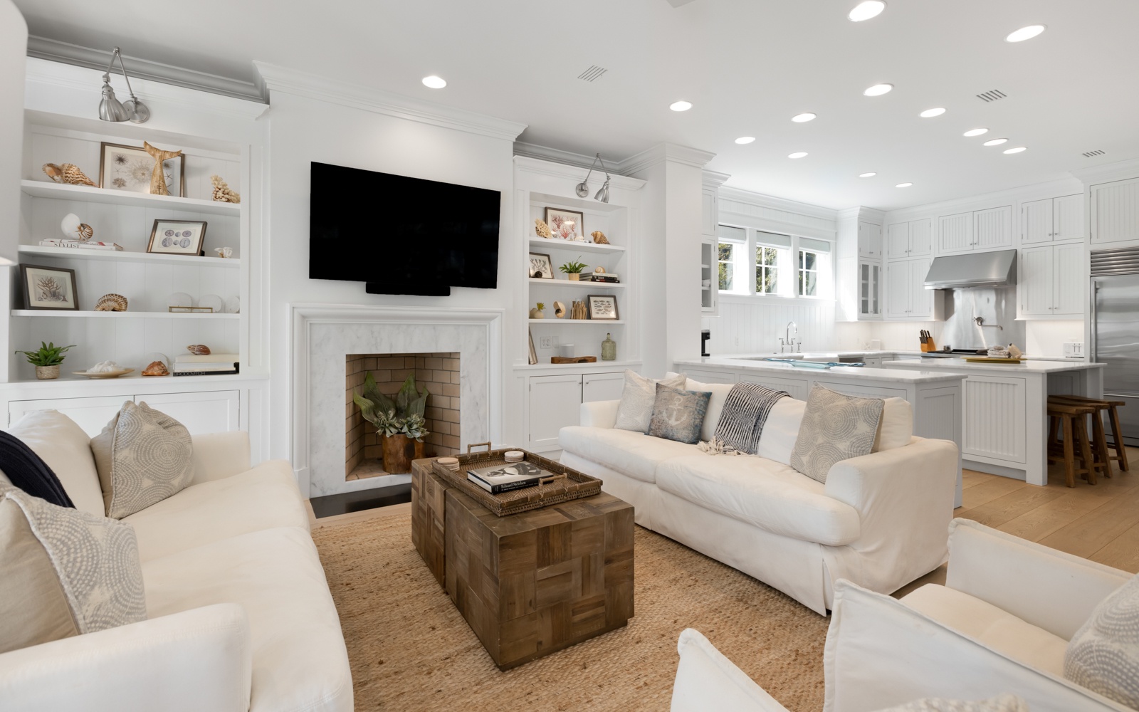 Sink into plush white sofas by the fireplace while your favorite shows play on the wall-mounted TV in this bright, open living space.