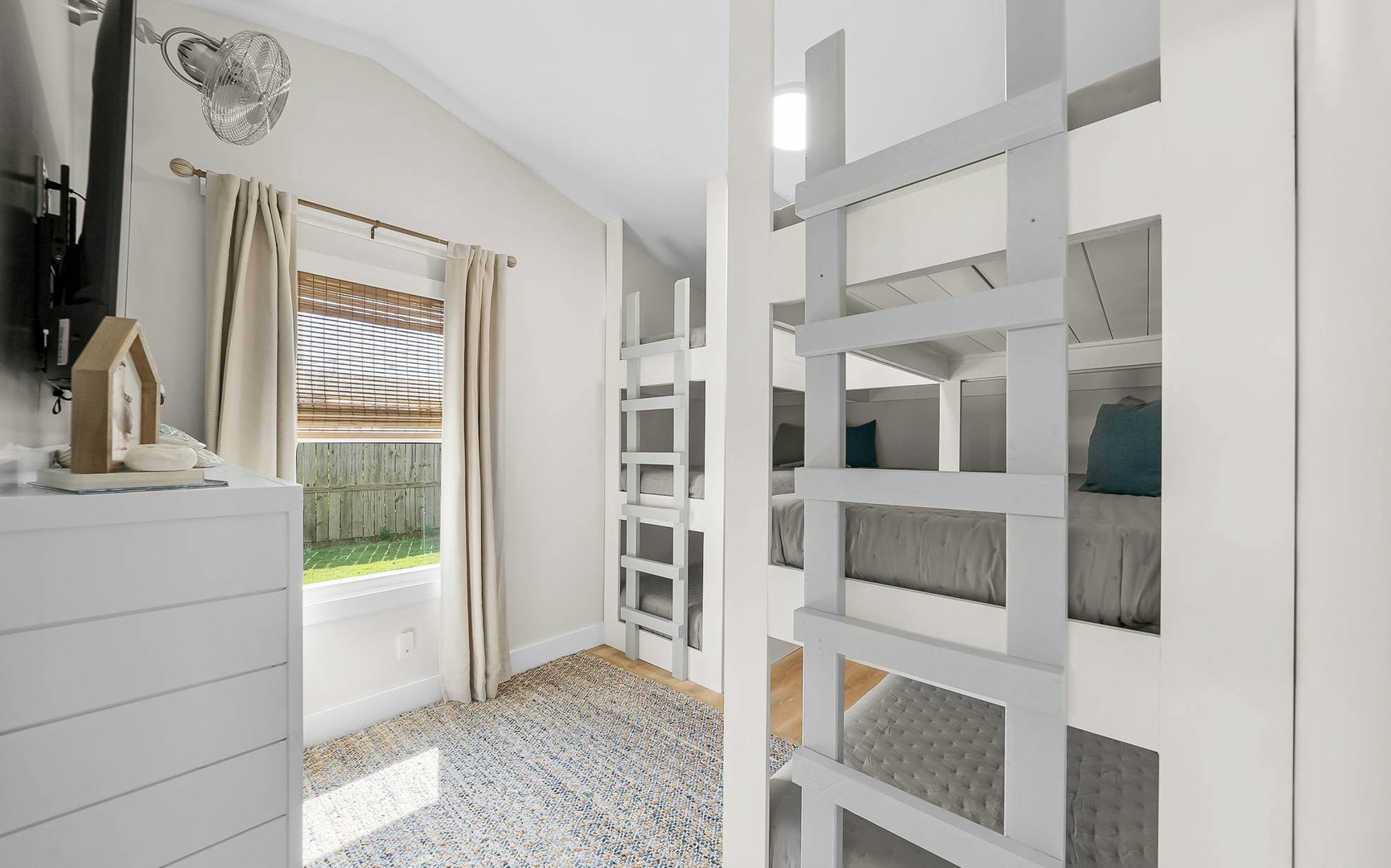 Sleep soundly in your custom white bunk beds with cozy gray linens and natural light streaming through bamboo shades.