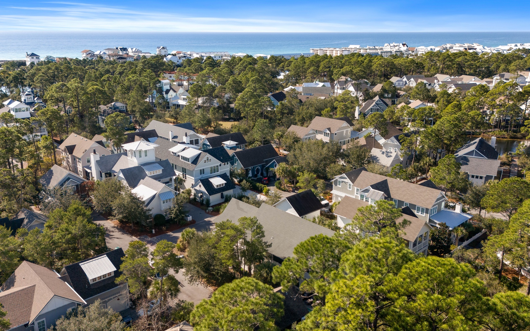 Aerial view of a charming coastal neighborhood with tree-lined streets and beach access nearby.