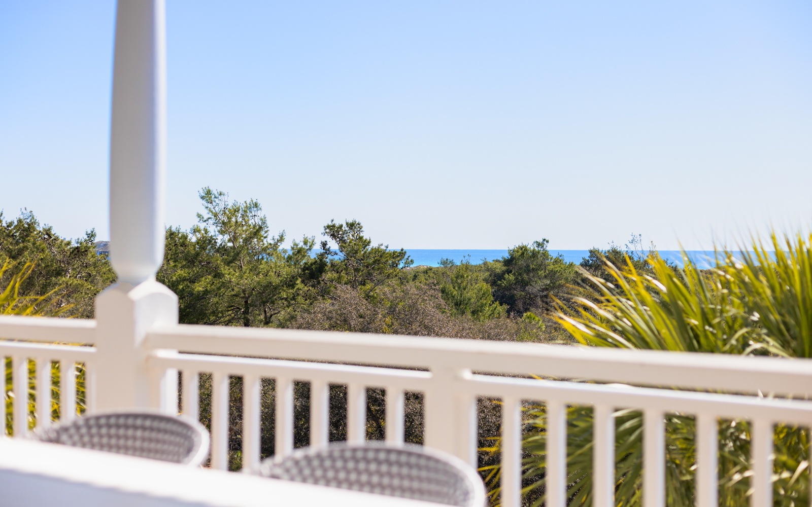 Peaceful balcony overlooks lush greenery and distant gulf views, creating the perfect spot for morning coffee or evening relaxation.