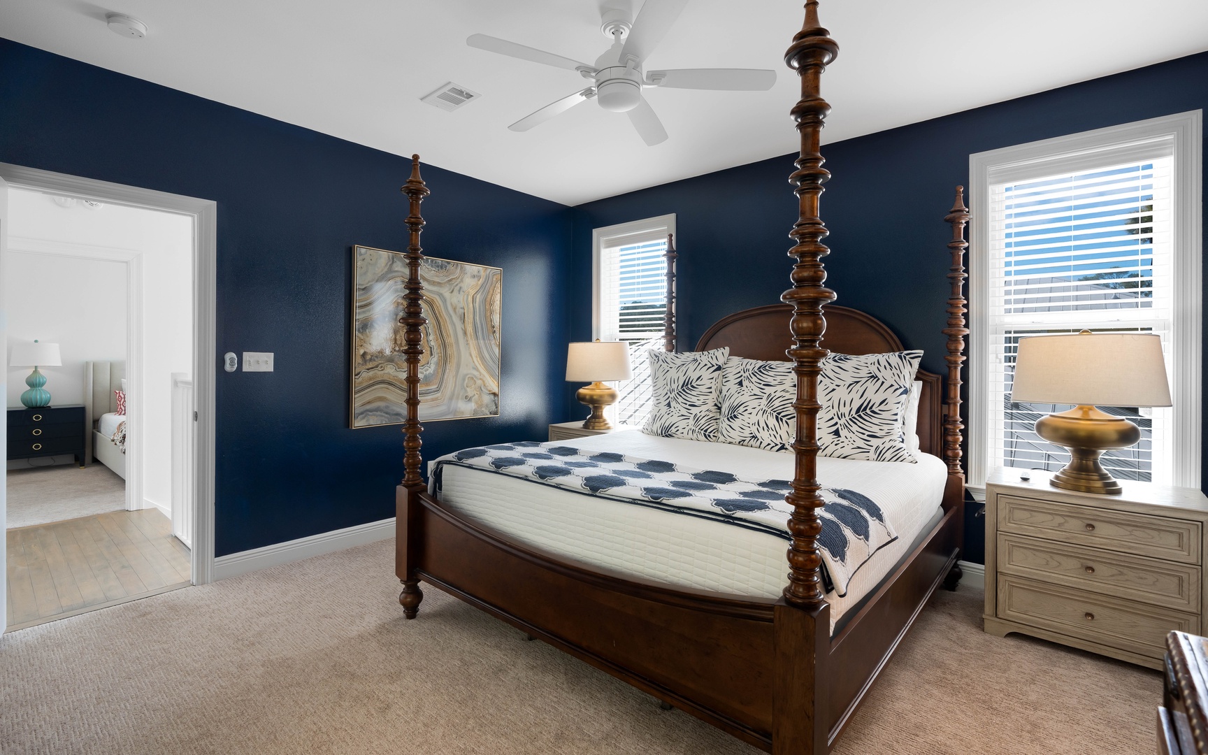Sink into this elegant four-poster bed surrounded by rich navy walls and coastal charm, creating your perfect retreat.