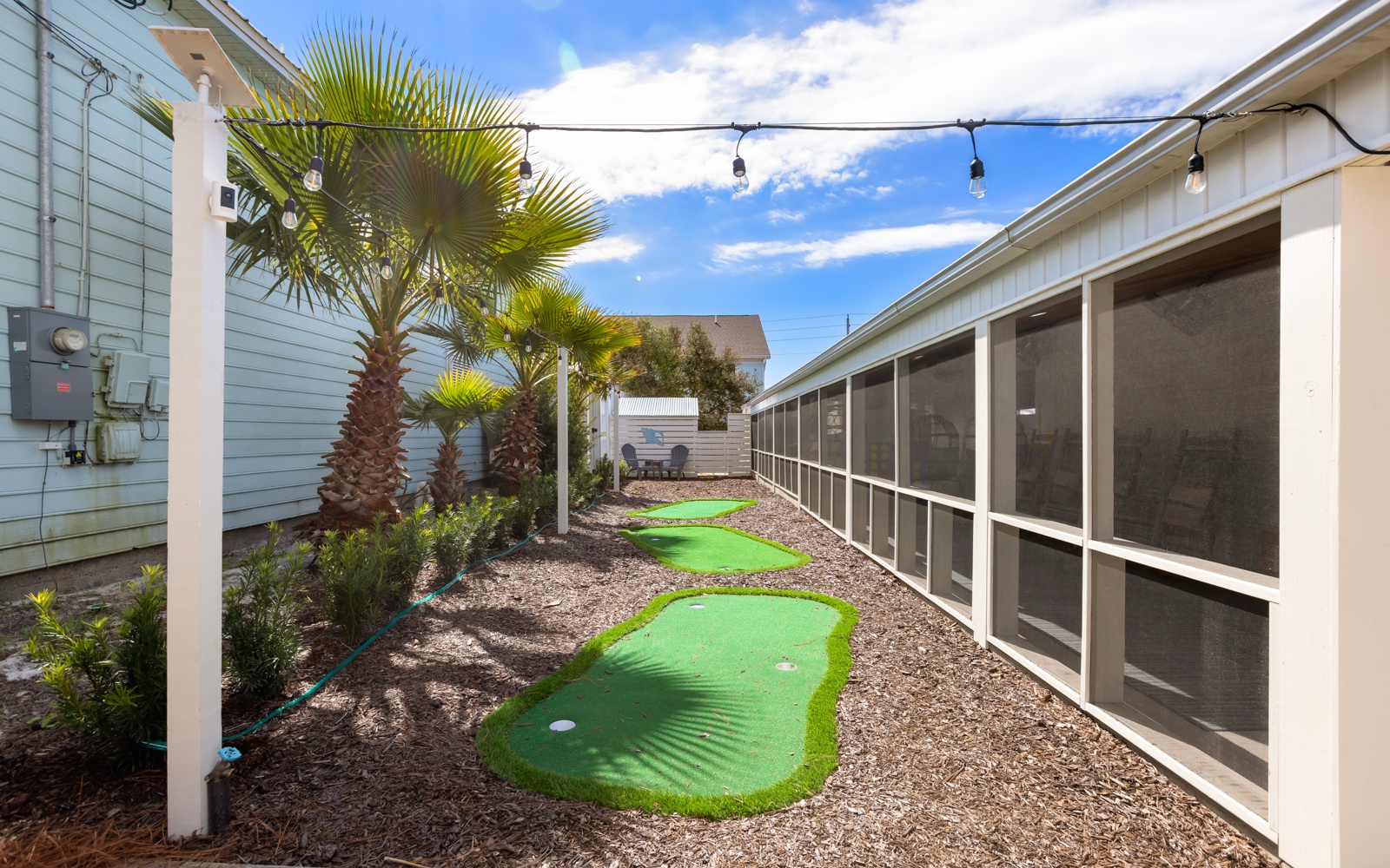 Your private mini golf course awaits under swaying palms and string lights, creating the perfect evening entertainment in your tropical backyard oasis.