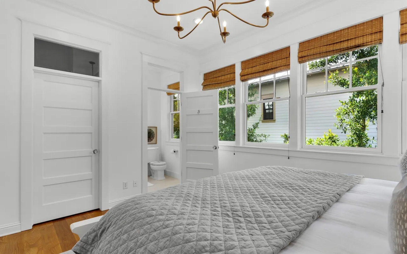 Wake up in your bright, serene bedroom where natural light streams through bamboo shades and leafy views create a peaceful retreat.