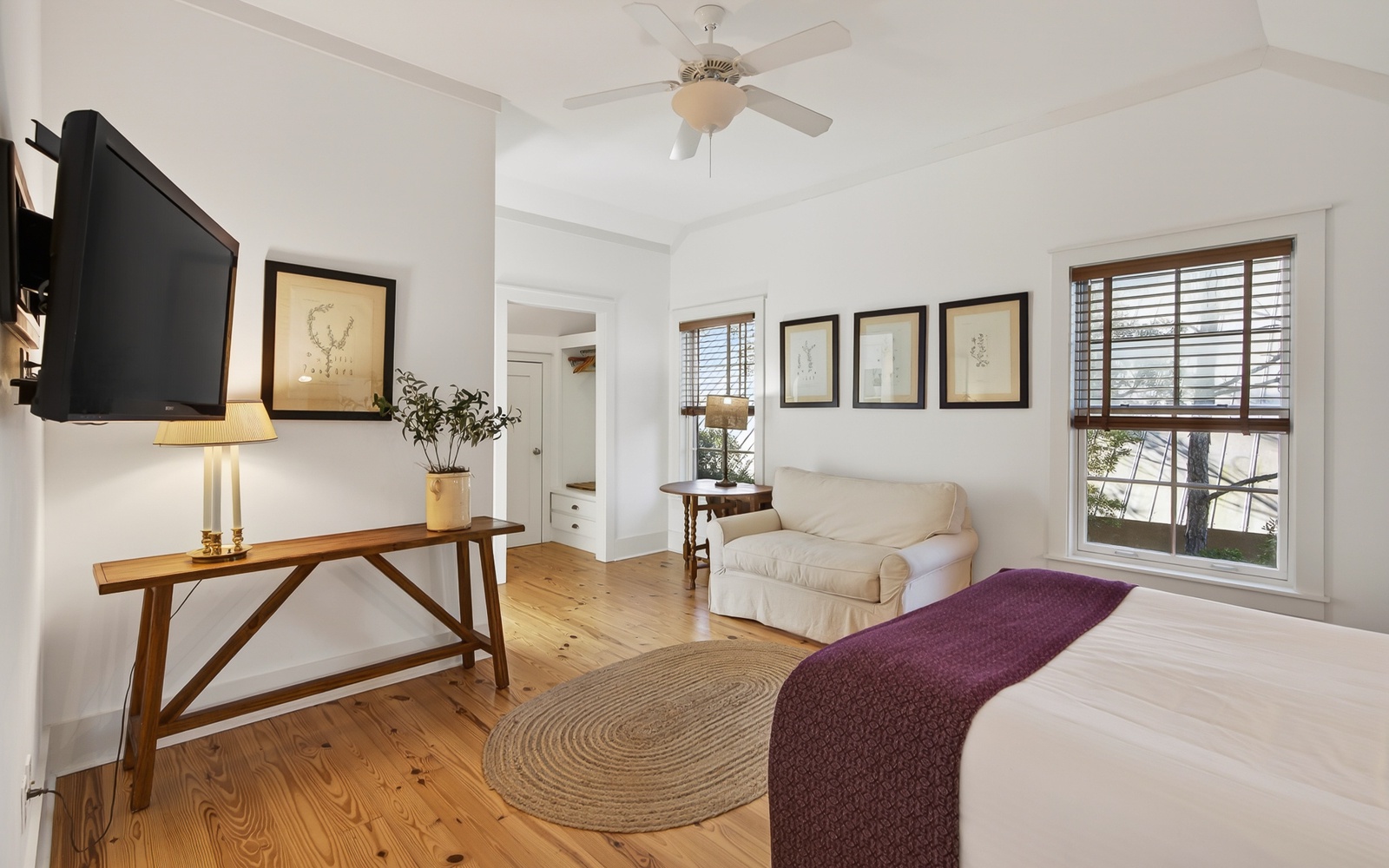 Your bright bedroom features hardwood floors, comfortable seating, and lovely natural light streaming through wooden blinds for peaceful rest.