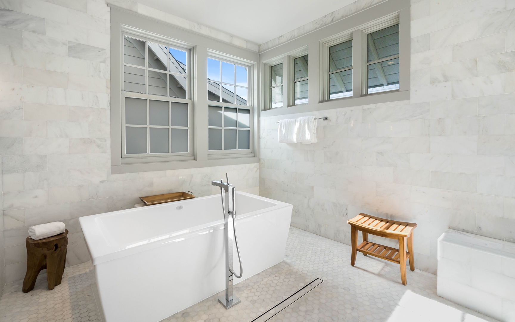 Sink into pure luxury in your marble sanctuary, where natural light dances across pristine surfaces and a soaking tub awaits your ultimate relaxation.