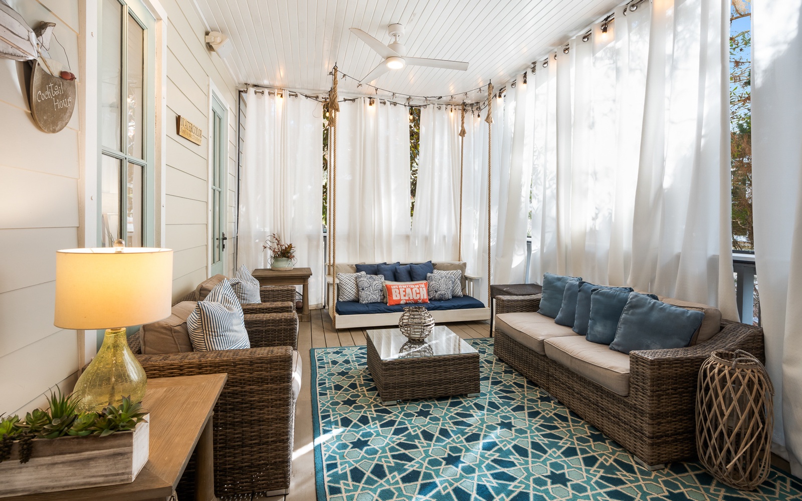 Unwind in your private screened porch with plush seating and flowing curtains that create the perfect coastal retreat for morning coffee or evening relaxation.
